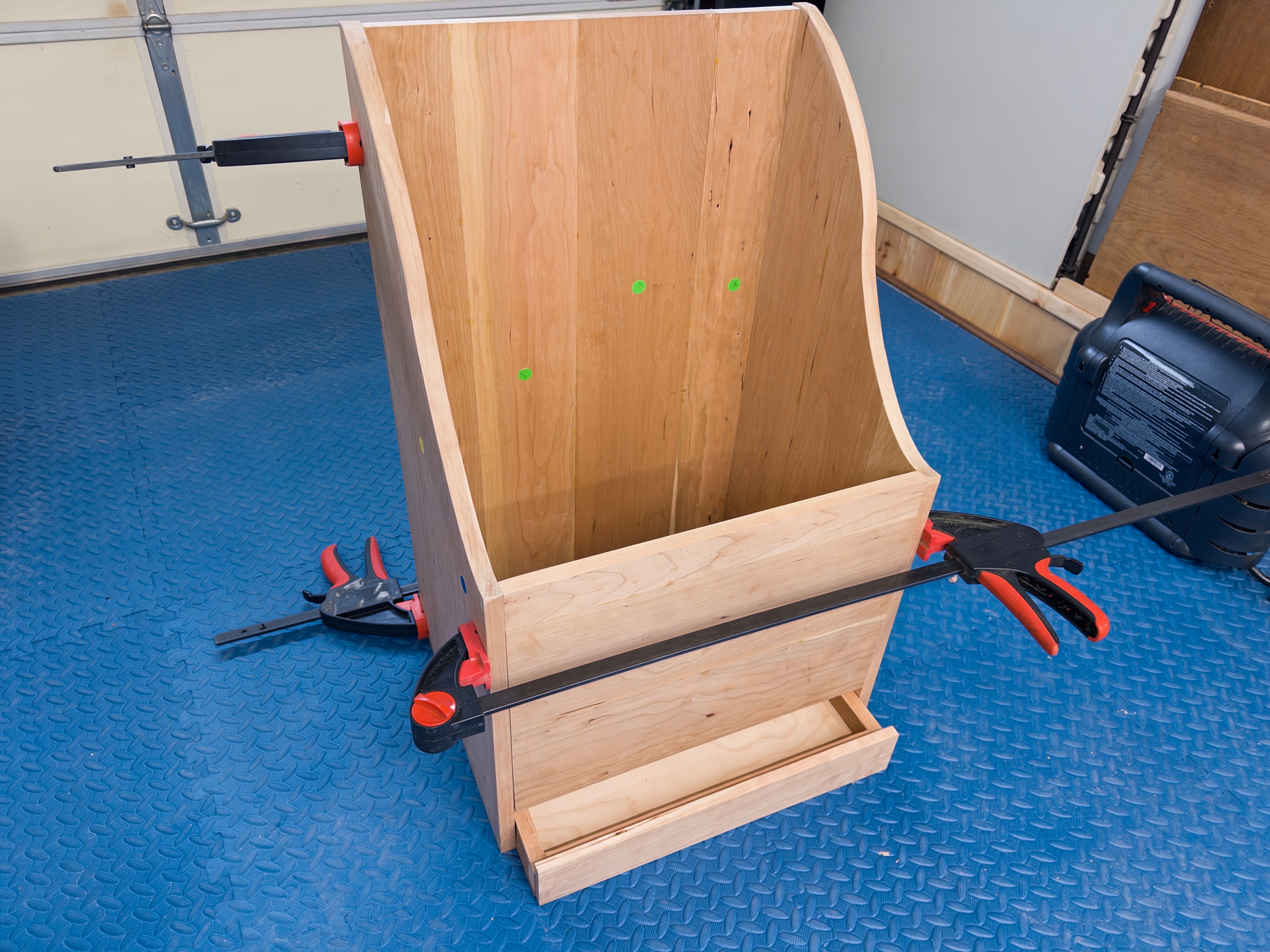 Cherry firewood box still under construction with clamps on it; with pullout box on the bottom to easily remove debris
